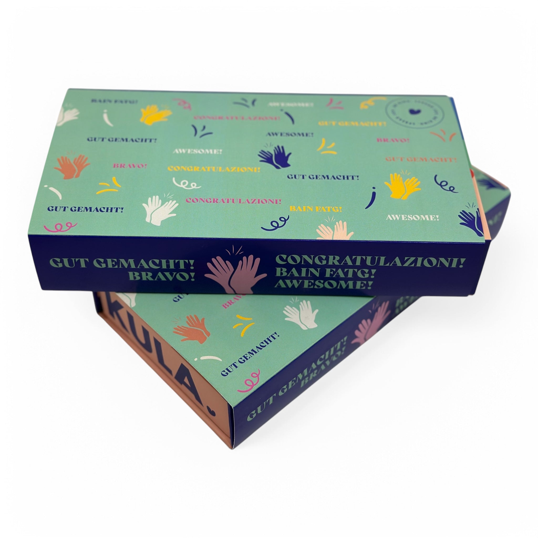 KULA congratulations gift box featuring a colourful 'Well Done' sleeve in multiple languages, paired with the signature KULA box. A perfect Swiss brownie gift to celebrate successes and milestones.