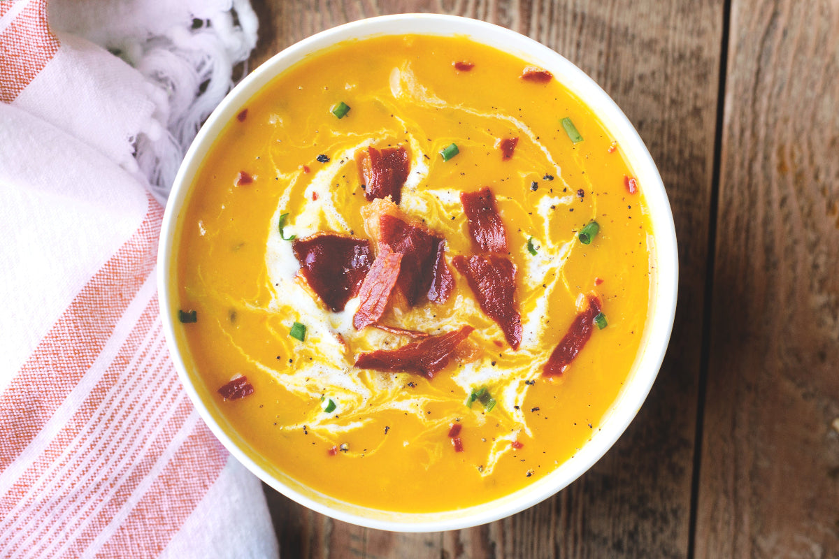 Comforting bowl of homemade soup topped with crispy bacon and fresh herbs, part of KULA’s upcoming Booster Box—a thoughtful gift for those feeling under the weather.