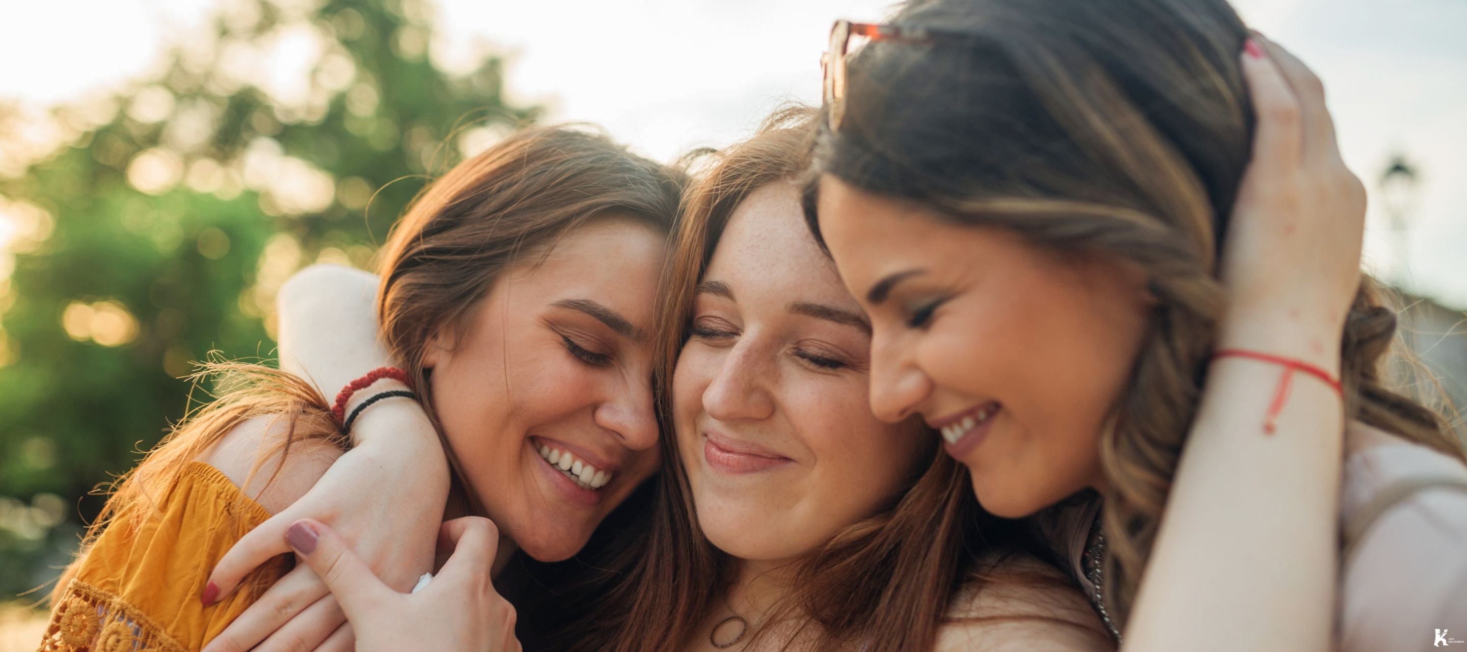 Three women hugging and smiling, symbolizing the joy and connection of KULA’s easy, personal, and memorable gifting experience.