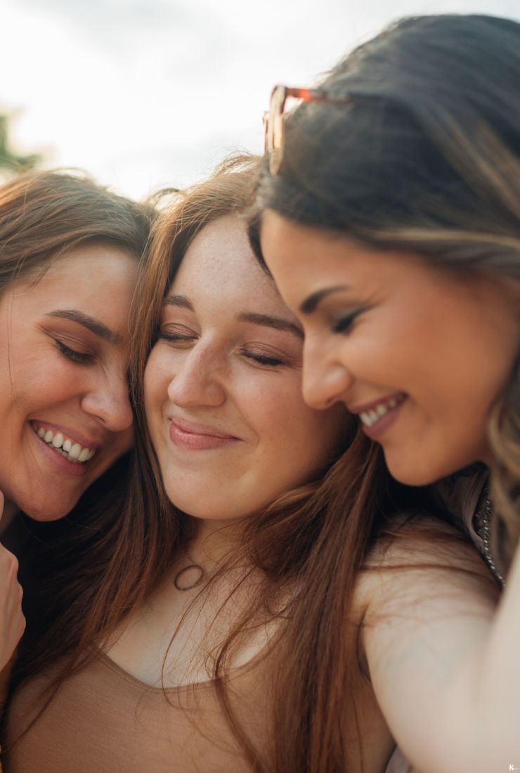 Three women hugging and smiling, symbolizing the joy and connection of KULA’s easy, personal, and memorable gifting experience.