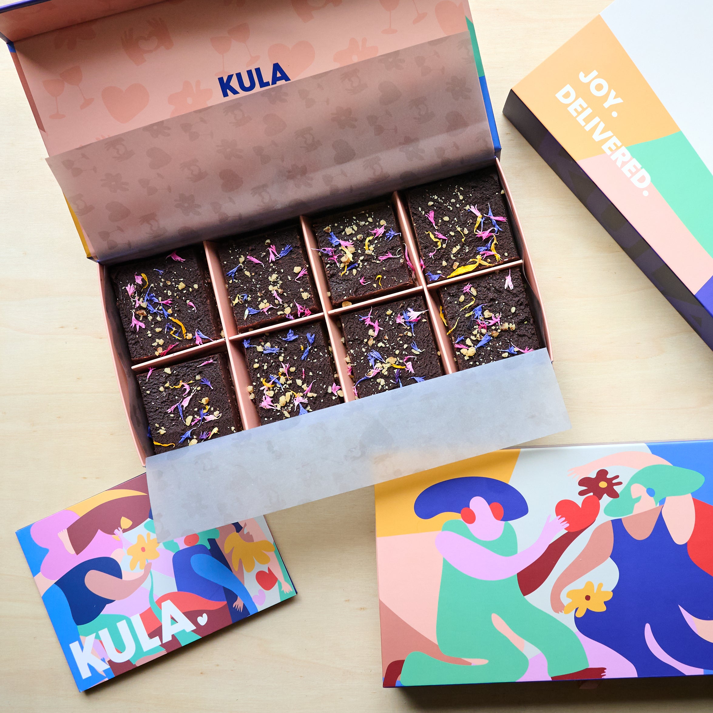 Colourful KULA gift box with 8 raw, vegan brownies topped with colourful edible flowers and nuts