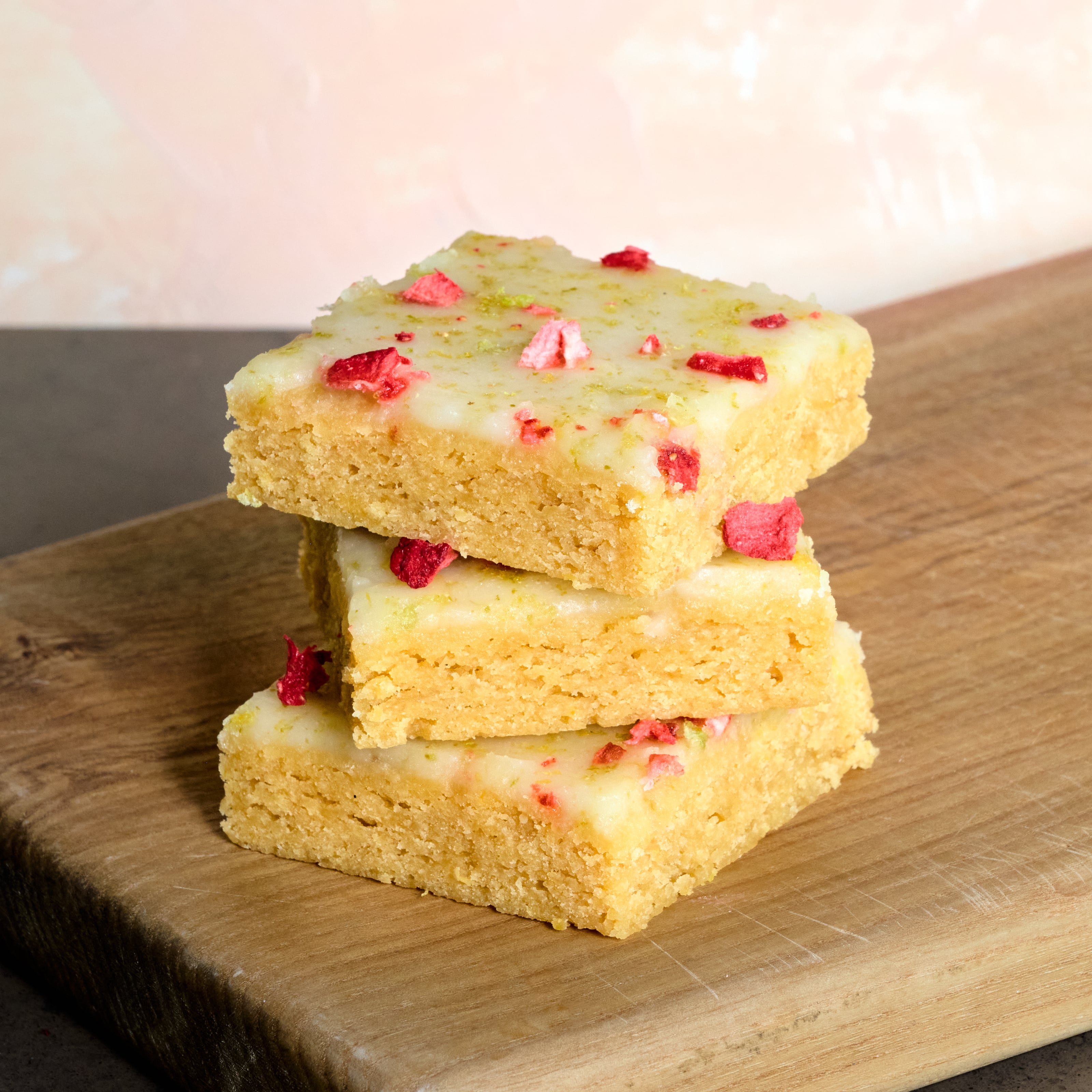 Stack of KULA Lemon and Lime Blondies with a lemon and lime zest glaze and freeze-dried raspberry topping. 