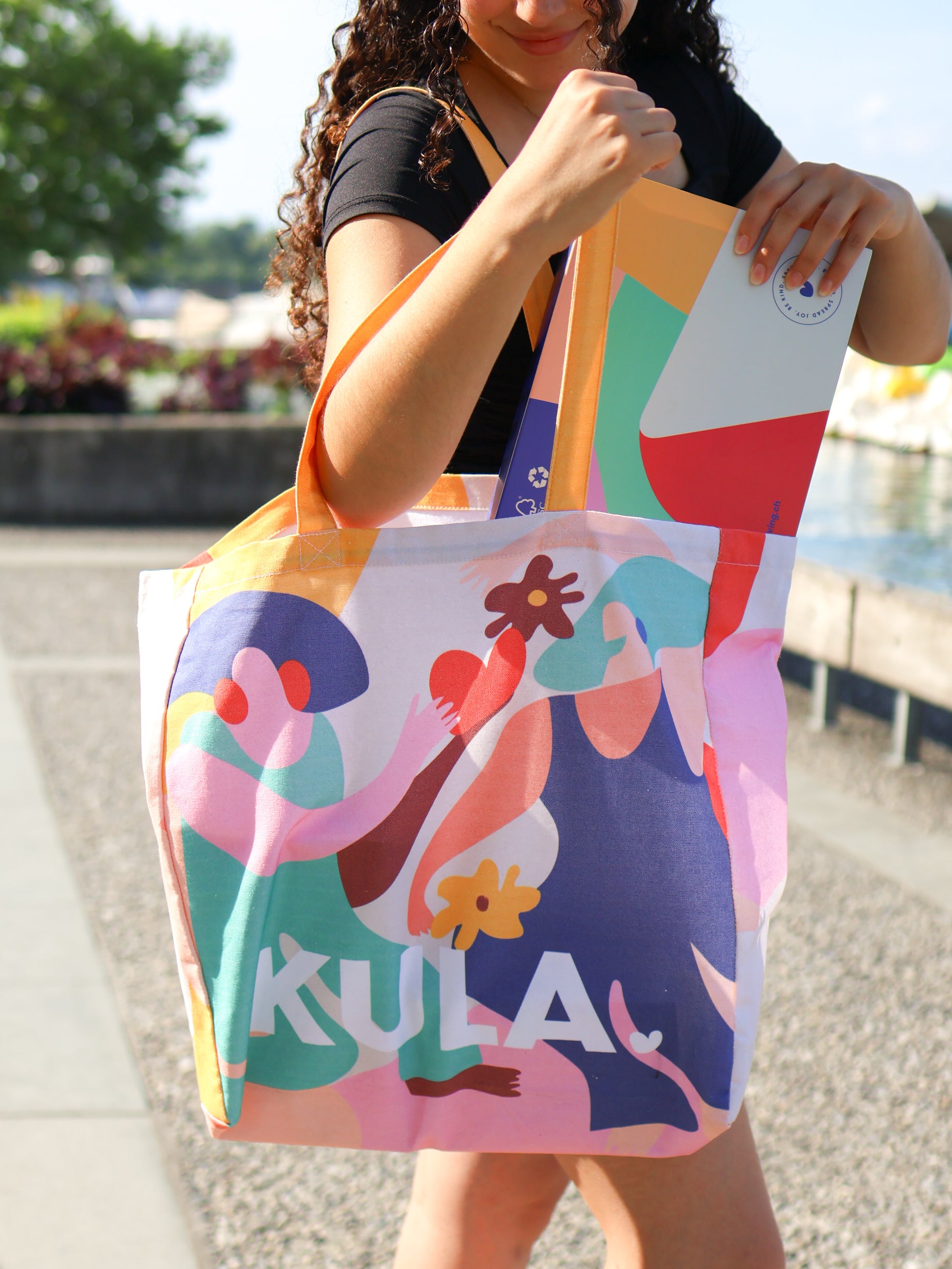 Picture of girl placing KULA box into KULA tote bag by Zürich lake