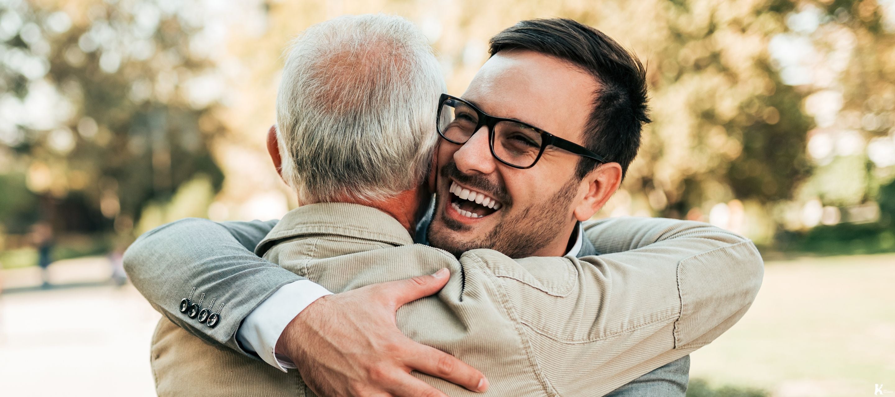 Two men embracing warmly outdoors, representing kindness, connection, and the spirit of KULA Kudos.