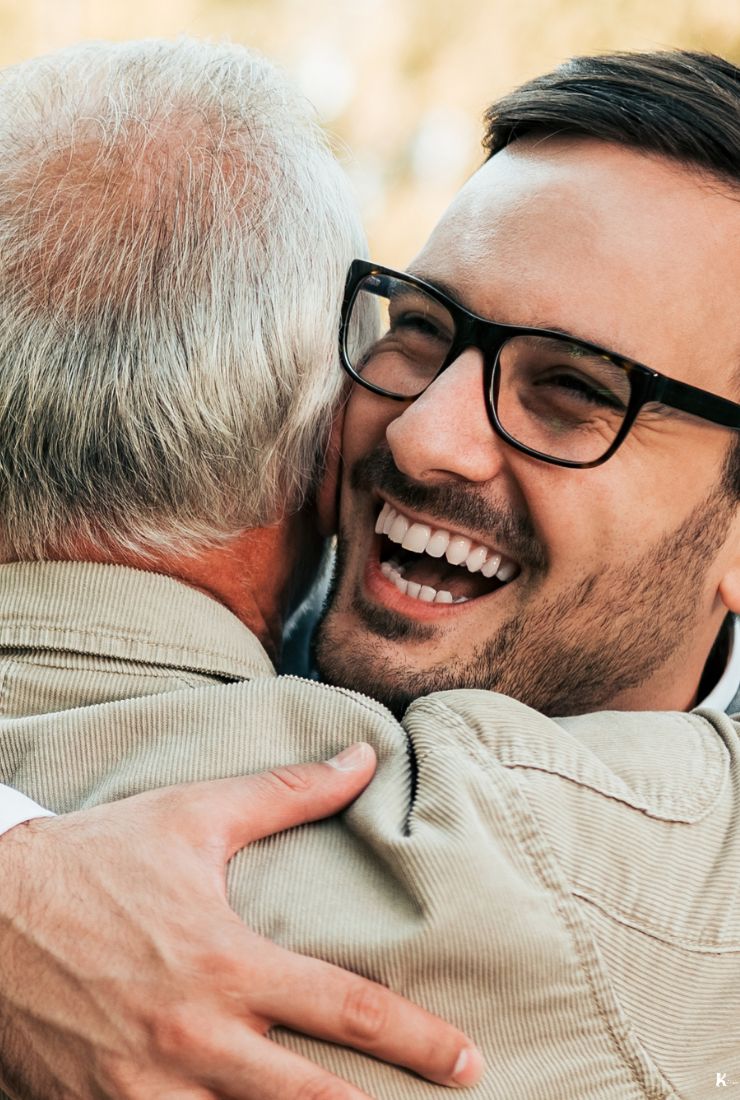 Two men embracing warmly outdoors, representing kindness, connection, and the spirit of KULA Kudos
